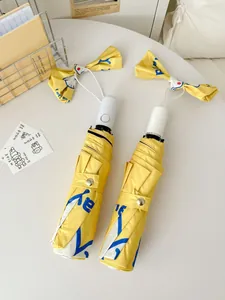 Macro detail view of yellow automatic umbrella featuring a cute bow and cartoon print