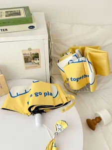 Yellow and white foldable umbrella with cute cartoon print in a cozy indoor setting