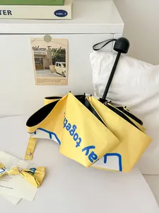 Close-up detail of yellow automatic folding sun umbrella with cute blue lettering