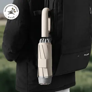 Automatic reverse folding umbrella with ring handle attached to a black backpack