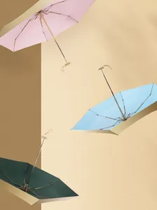 Artistic display of compact pink blue and green umbrellas against a neutral background