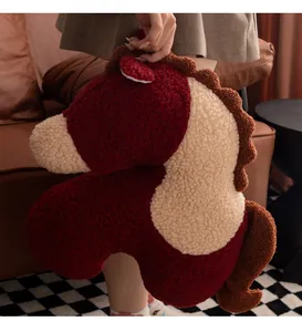 Vue détaillée d'un oreiller en peluche cheval rouge et crème tenu par une femme