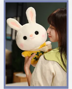 Detailed view of a cute white rabbit plush doll wearing a yellow sweater being held