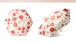 Detailansicht eines Mini-Taschensonnenschirms mit elegantem roten Blumenmuster auf Weiß