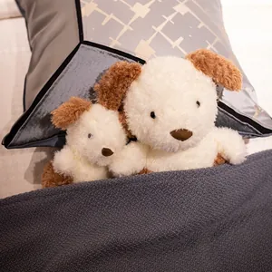 Paire de peluches chiots blanches aux oreilles brunes sur un lit gris douillet