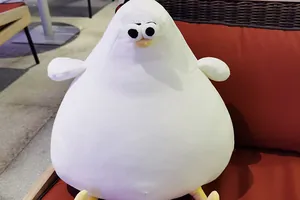 Adorable round white Danish seagull plush bird toy resting on a soft red sofa cushion