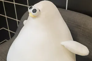 Close-up detail of a soft white Danish seagull plush toy on a gray chair