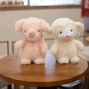 Paire de jolies peluches cochon rose et mouton crème pour enfants posées sur une table