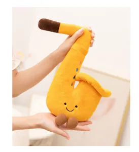 Detailed view of a soft yellow saxophone plush toy with a smiley face held by hands