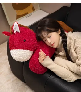 Cozy lifestyle view of a soft red horse plush pillow being held by a girl on a sofa.