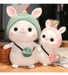 Detailed view of two cute white bunny plush toys wearing dinosaur and unicorn hoods