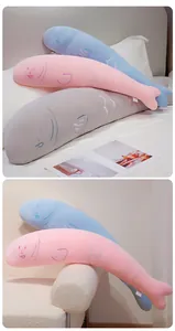 Vue détaillée de coussins en peluche longs en forme de poisson crème sur un lit et une chaise
