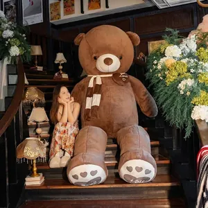 Giant brown plush teddy bear stuffed animal toy with heart details and scarf on stairs