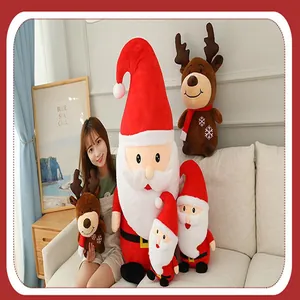 Assorted sizes of plush Santa Claus and reindeer toys in a cozy indoor setting