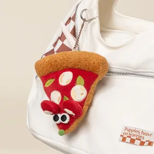 Adorable llavero de peluche de ratón de pizza colgado en un bolso de lona blanca.