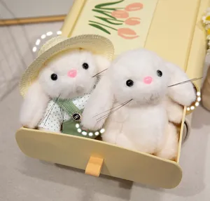 Detailed view of two cute white plush bunnies in a decorative yellow suitcase