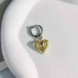 Dettaglio di un ciondolo a cuore dorato in stile vintage su un orecchino argento
