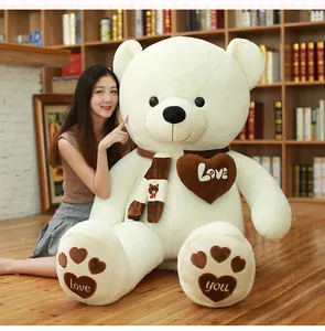 Macro view of giant white plush teddy bear featuring a scarf and love heart patches