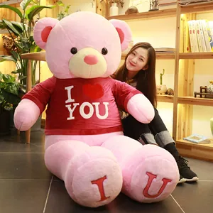 Giant pink teddy bear plush toy wearing I LOVE YOU red shirt in cozy home setting