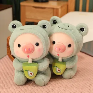Pareja de peluches de cerdito con disfraz de rana verde y taza de té de aguacate