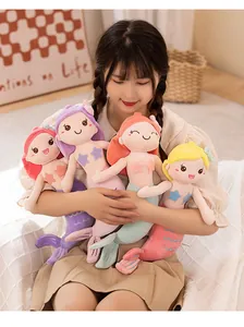 Model holding a collection of four colorful mermaid plush dolls with soft pastel hair