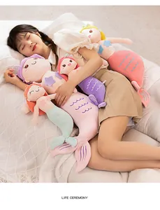 Soft mermaid plush dolls held by a girl in a cozy and comfortable bedroom scene