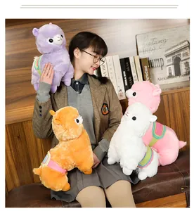 Adorable alpaca plush toys in four vibrant colors held by a model in a cozy interior