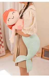 Soft mermaid plush doll held by a person showing its large size and cuddly texture.