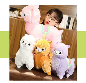 Close-up of colorful alpaca plush toys with rainbow saddles in a cozy room setting.