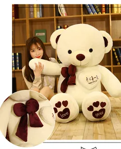 Detailed view of a giant cream teddy bear featuring a soft dark red velvet bow tie