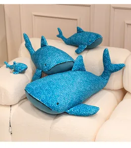 Set of various sizes blue whale shark plush toys with white dots on a cozy beige sofa