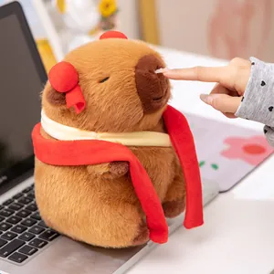 Adorable peluche de carpincho marrón disfrazado de Nezha con lazos rojos y bufanda
