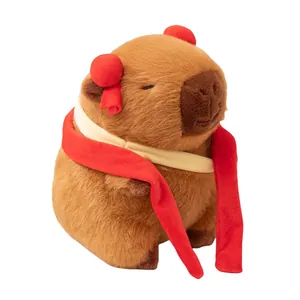 Adorable peluche de carpincho Nezha marrón con moños rojos sobre un fondo blanco puro