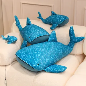 Soft blue whale shark plush toys in various sizes resting on a cozy white sofa