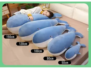 Selection of blue whale plush pillows in multiple sizes from 50cm to 150cm on bed