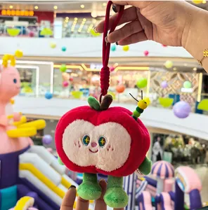 Close-up of a cute red apple plush keychain with a tiny green caterpillar detail