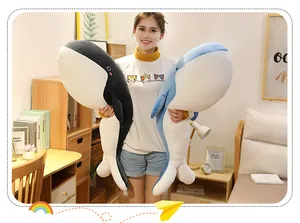 Large whale plush pillow shown held by a model to display the size in a home bedroom setting