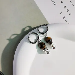 Primo piano di una perla occhio di tigre e distanziali su un orecchino a cerchio punk.