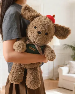Close-up of a cute brown curly-haired plush teddy dog with a red hat and green vest