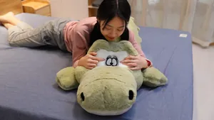 Grand oreiller en peluche crocodile vert pour un confort de sommeil sur un lit douillet