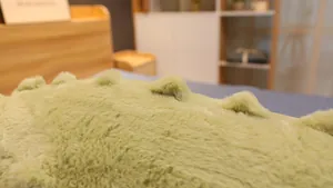 Gros plan sur la texture douce en fausse fourrure verte d'un grand oreiller crocodile