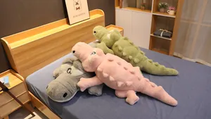 Grands oreillers en peluche crocodile doux en vert rose et gris sur un lit douillet