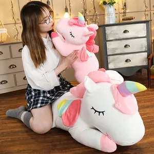 Grande cuscino di peluche a forma di unicorno con corno arcobaleno in un ambiente accogliente