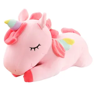 Cuscino peluche unicorno rosa con corno e ali arcobaleno in posa da addormentato.