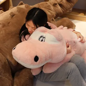 Grand oreiller en peluche crocodile rose géant tenu par une femme dans un décor douillet