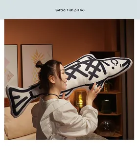 Asian woman holding large salted fish plush pillow with black doodle patterns in a cozy bedroom