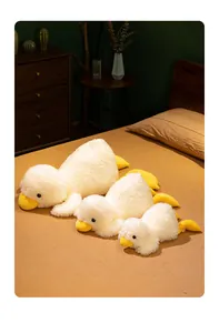 Detailed view of three soft plush duck toys in various sizes on a cozy bed.