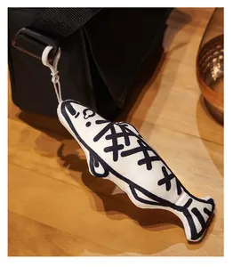 Detailed macro view of a creative salted fish plush pendant hanging on a black nylon bag strap