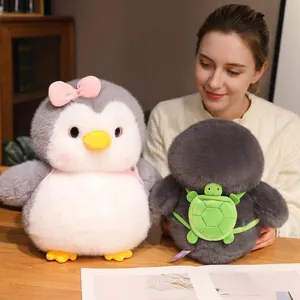 Soft chubby penguin plush toy with a cute green turtle backpack accessory shown on a desk