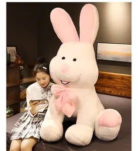 Giant long-eared rabbit plush toy shown sitting on a bed for scale reference.